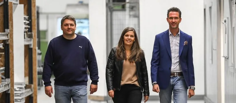 Three employees walking through a workspace