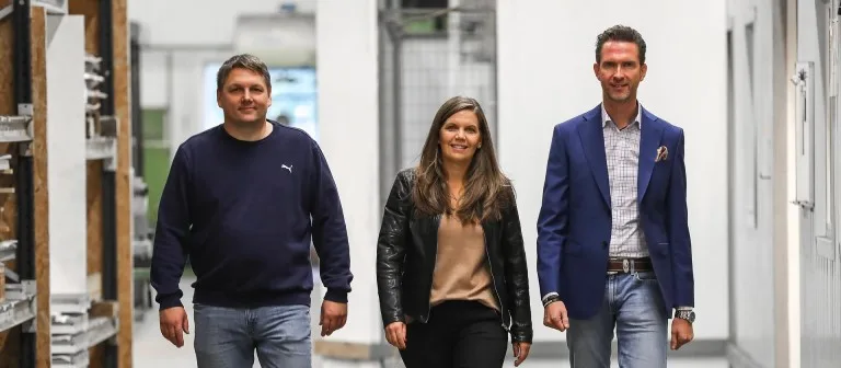 Tre medarbeidere som går gjennom et lokale